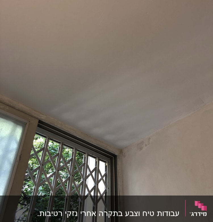 קיר ותקרה צבועים בלבן עם סימני תיקון